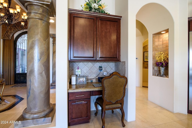 interior space featuring light tile patterned floors, arched walkways, light countertops, tasteful backsplash, and built in desk