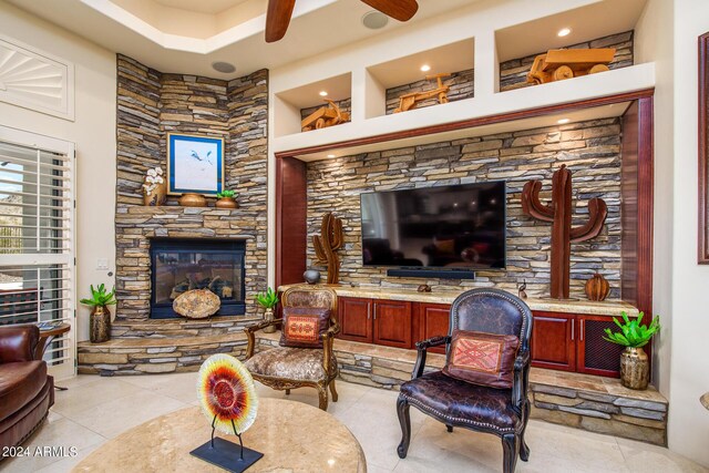 living room featuring light tile patterned floors, a ceiling fan, and a stone fireplace