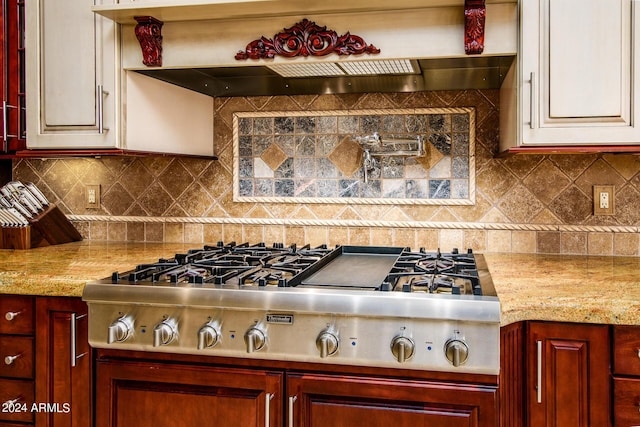 kitchen featuring light stone counters, reddish brown cabinets, stainless steel gas cooktop, and decorative backsplash