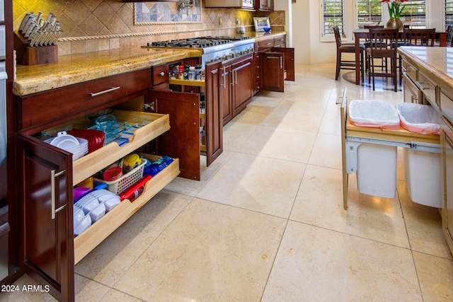 kitchen with light tile patterned flooring, stainless steel gas cooktop, light stone countertops, and tasteful backsplash