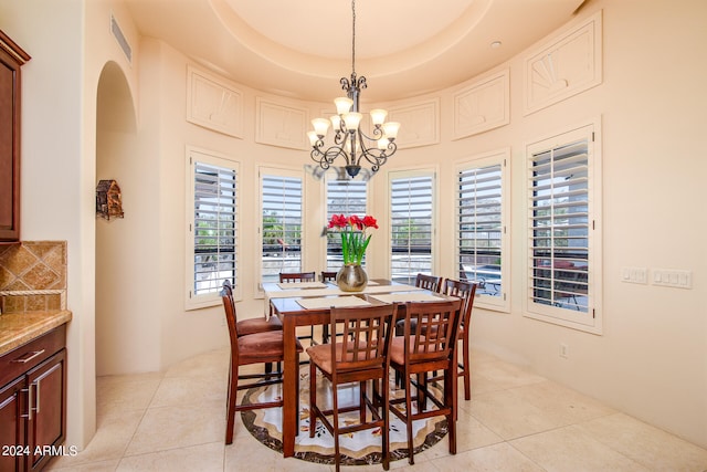 tiled dining space featuring a notable chandelier, a wealth of natural light, and a tray ceiling