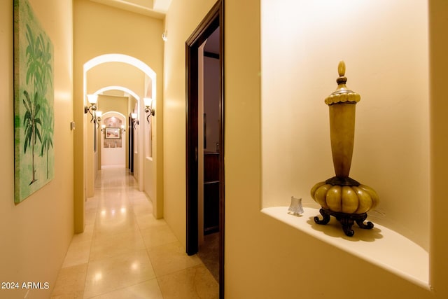 corridor with light tile patterned floors and arched walkways