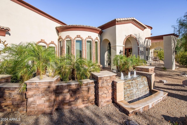 exterior space with a tile roof and stucco siding