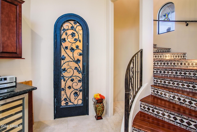 stairs featuring wine cooler, tile patterned flooring, and arched walkways