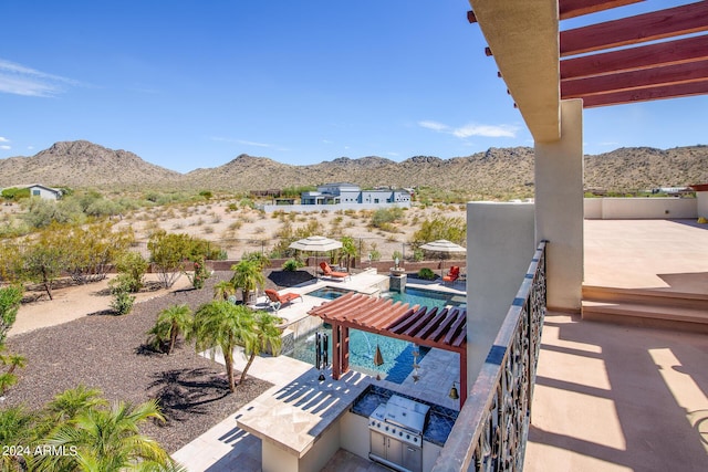 view of patio with a fenced in pool, an outdoor kitchen, a grill, a mountain view, and fence