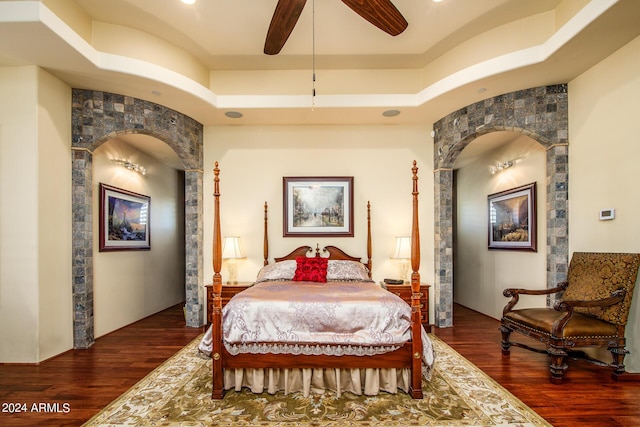 bedroom featuring dark wood-style floors, a tray ceiling, and a ceiling fan