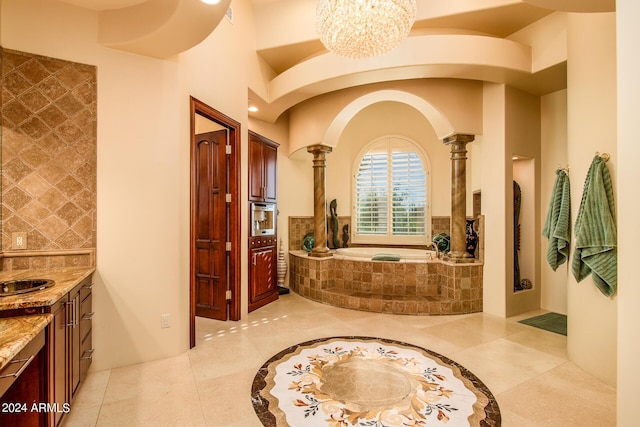 bathroom with decorative columns, tasteful backsplash, vanity, a chandelier, and a bath