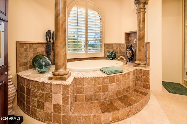 bathroom with a garden tub, decorative columns, and tile patterned floors