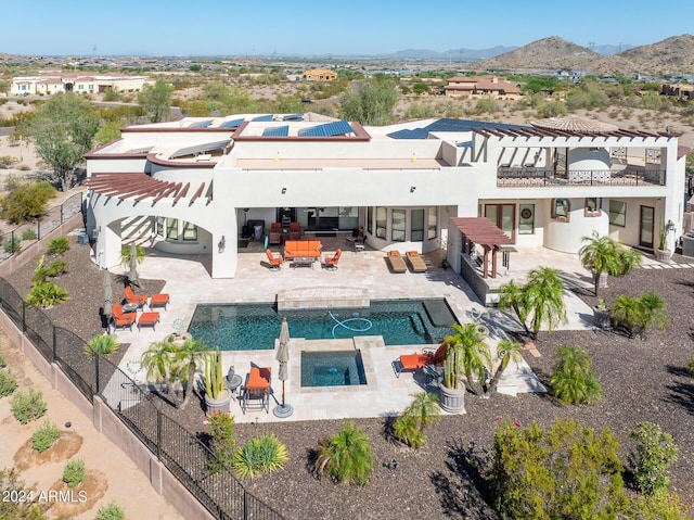 back of property featuring a fenced backyard, an in ground hot tub, a patio area, roof mounted solar panels, and a mountain view