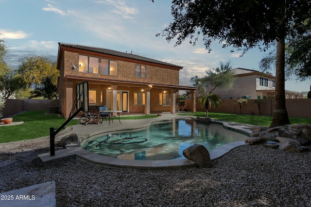 back of house featuring a yard, a fenced in pool, and a patio area