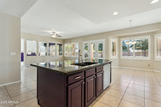 kitchen with sink, hanging light fixtures, light tile patterned floors, stainless steel dishwasher, and an island with sink