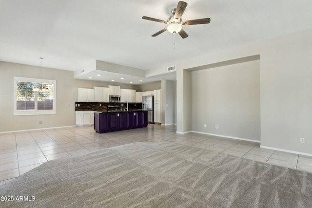 unfurnished living room featuring ceiling fan with notable chandelier and light tile patterned floors