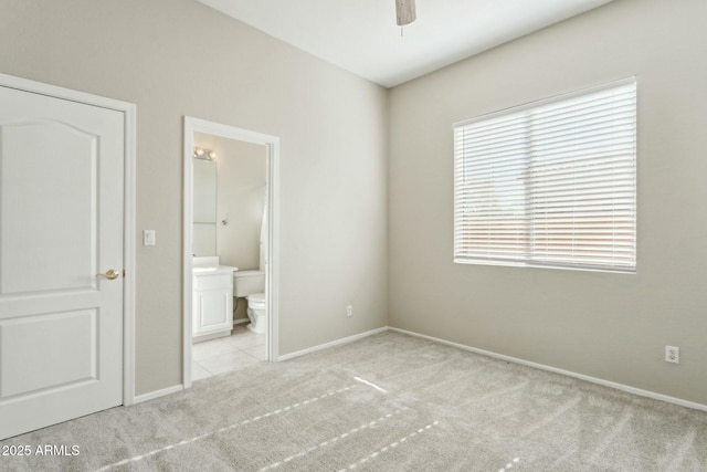 unfurnished bedroom featuring light carpet, ceiling fan, and ensuite bathroom