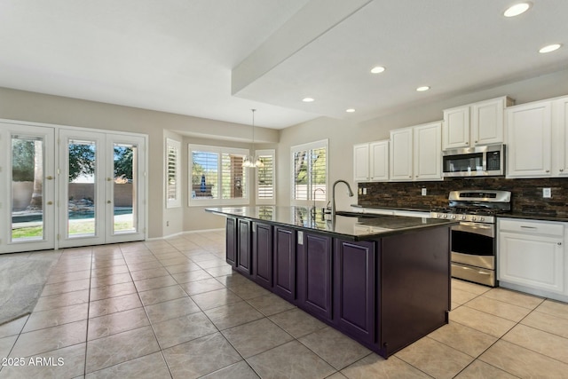 kitchen featuring light tile patterned flooring, stainless steel appliances, hanging light fixtures, and a center island with sink