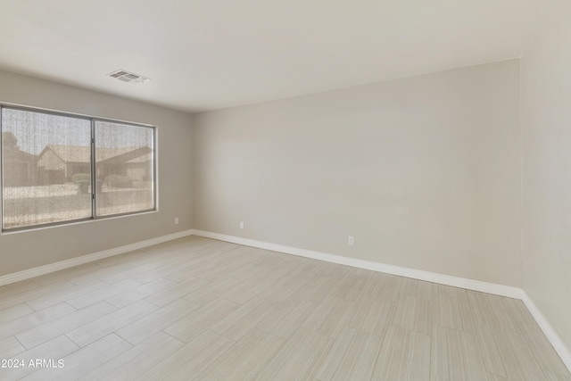 unfurnished room featuring lofted ceiling, baseboards, visible vents, and track lighting