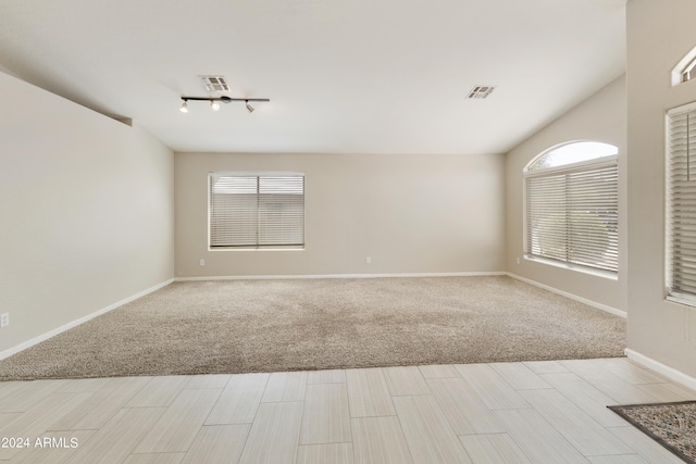 foyer entrance with vaulted ceiling, visible vents, plenty of natural light, and light carpet