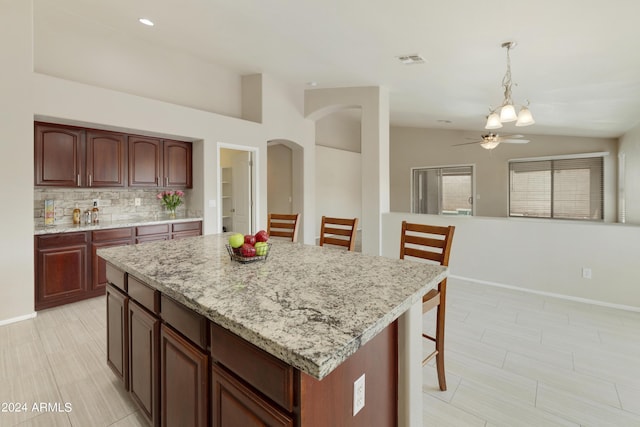 kitchen featuring a center island, decorative light fixtures, lofted ceiling, visible vents, and a kitchen bar