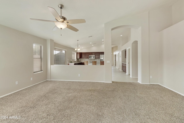 unfurnished living room featuring lofted ceiling, baseboards, a ceiling fan, and light colored carpet