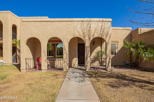 view of front of home with covered porch, a front lawn, and stucco siding