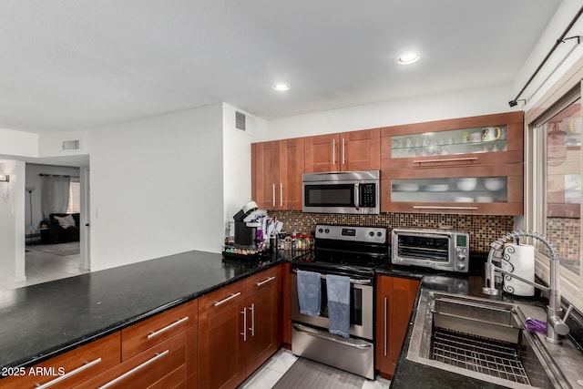 kitchen featuring appliances with stainless steel finishes, visible vents, a sink, and backsplash