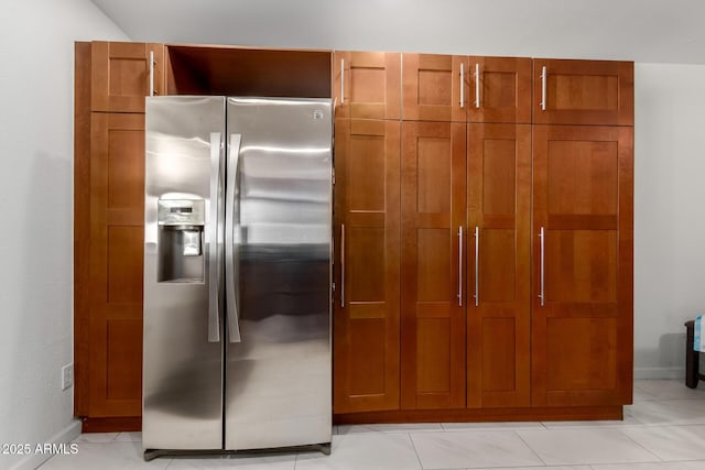 kitchen featuring brown cabinets, baseboards, and stainless steel refrigerator with ice dispenser