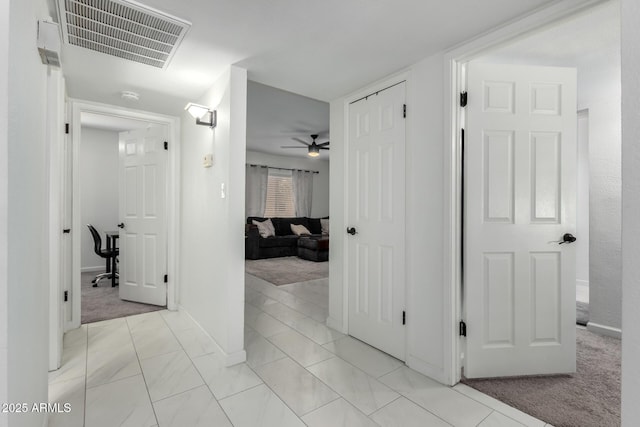 hall featuring light colored carpet, visible vents, and baseboards