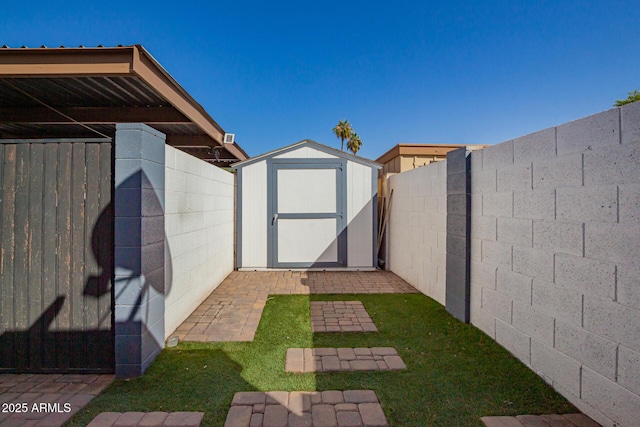 view of yard featuring a storage shed, a fenced backyard, and an outdoor structure