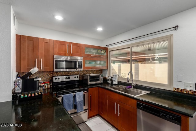 kitchen with a toaster, stainless steel appliances, backsplash, glass insert cabinets, and a sink