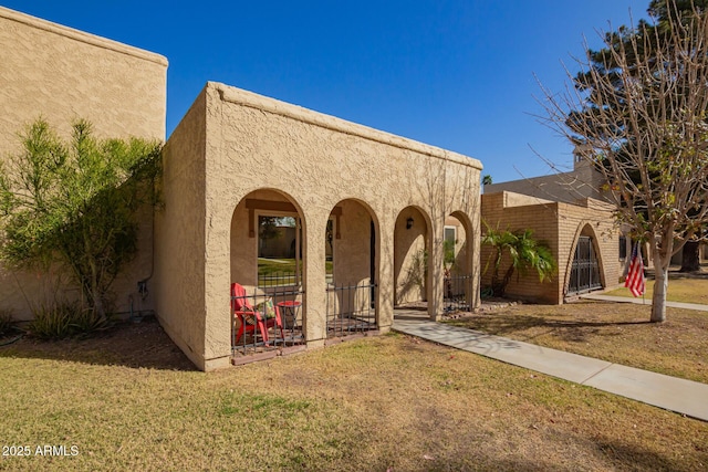 view of front of home featuring covered porch, a front lawn, and stucco siding