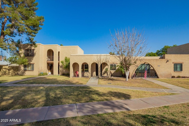 pueblo revival-style home with a front yard and stucco siding