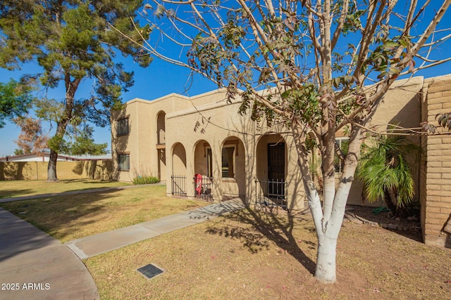 view of front of property with covered porch, fence, a front lawn, and stucco siding