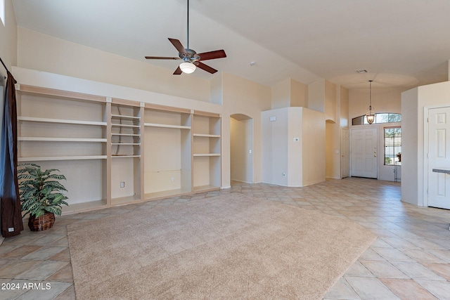 unfurnished living room with ceiling fan, light tile patterned floors, and a high ceiling