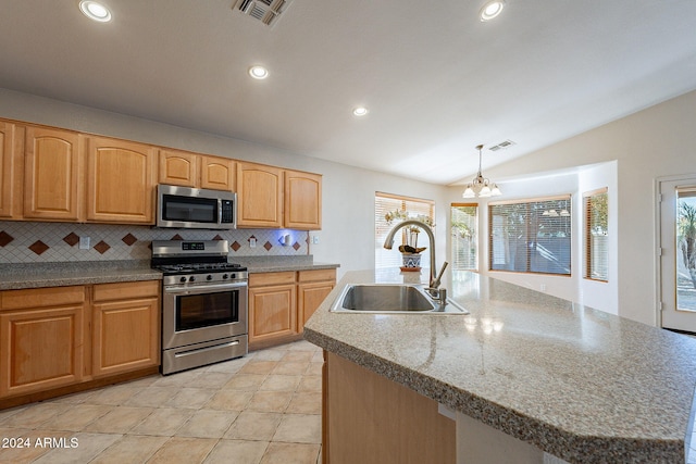 kitchen with sink, stainless steel appliances, pendant lighting, lofted ceiling, and a center island with sink