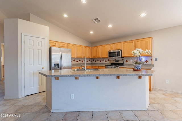 kitchen with decorative backsplash, lofted ceiling, stainless steel appliances, and an island with sink