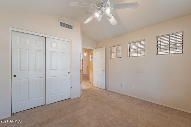 unfurnished bedroom with ceiling fan, light colored carpet, lofted ceiling, and a closet