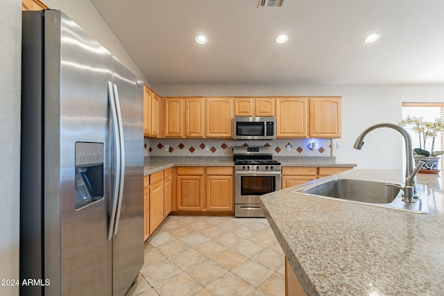 kitchen featuring sink, light brown cabinets, tasteful backsplash, light tile patterned floors, and appliances with stainless steel finishes