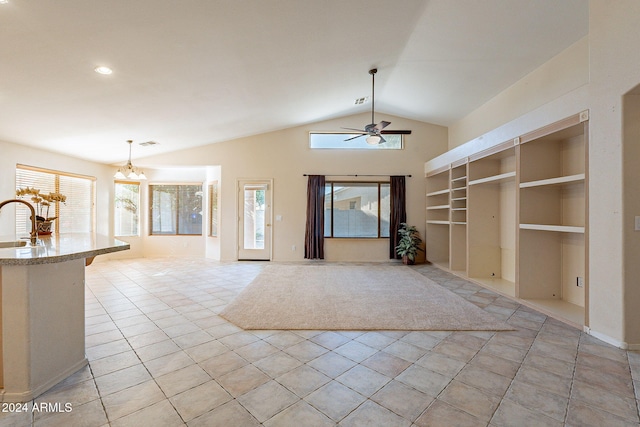 unfurnished living room featuring built in shelves, ceiling fan with notable chandelier, vaulted ceiling, sink, and light tile patterned flooring