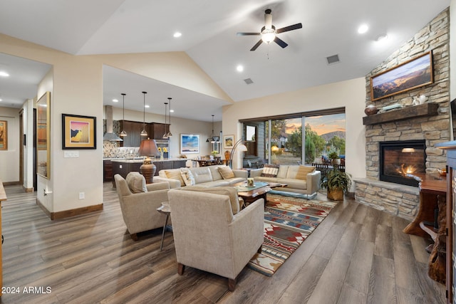 living room with a stone fireplace, high vaulted ceiling, dark wood-type flooring, and ceiling fan