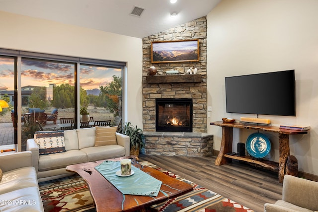 living room with a stone fireplace, hardwood / wood-style flooring, and vaulted ceiling