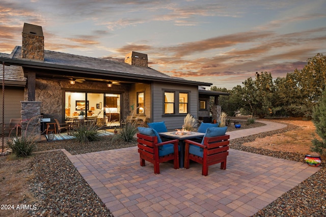 patio terrace at dusk featuring ceiling fan and a fire pit