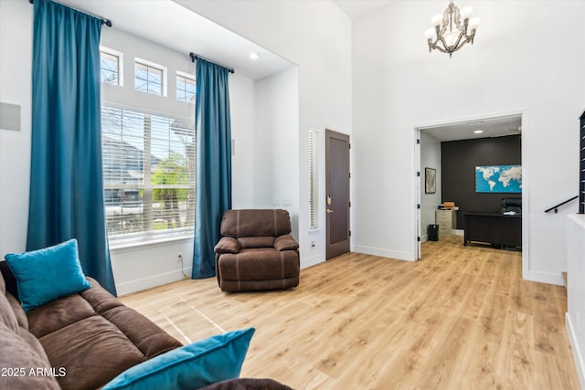 living room featuring a high ceiling, a notable chandelier, wood finished floors, and baseboards