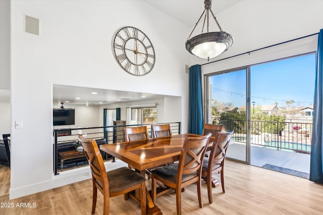 dining room featuring light wood-type flooring, baseboards, a high ceiling, and visible vents