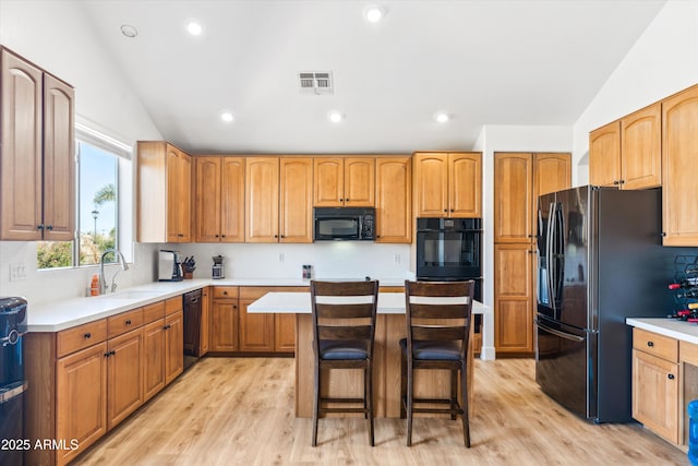 kitchen with visible vents, black appliances, lofted ceiling, and a sink