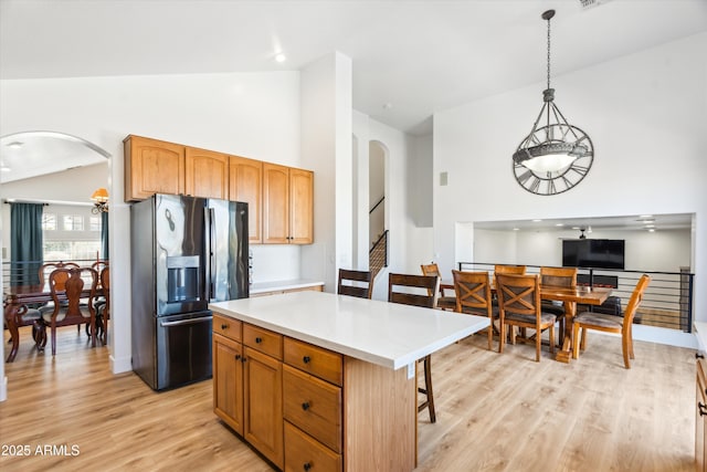 kitchen featuring arched walkways, vaulted ceiling, light countertops, and black refrigerator with ice dispenser