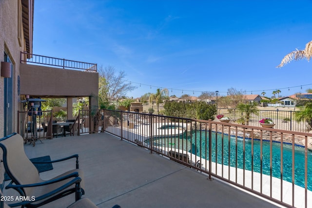 view of patio featuring a balcony, a pool with connected hot tub, and fence