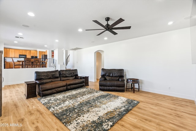 living area with arched walkways, visible vents, recessed lighting, and light wood-type flooring