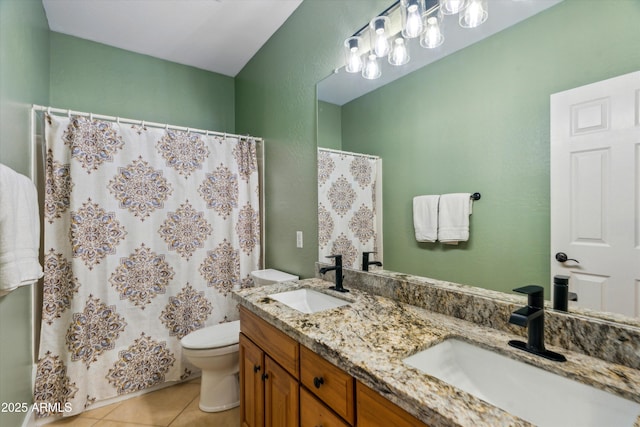 bathroom with a sink, toilet, double vanity, and tile patterned floors