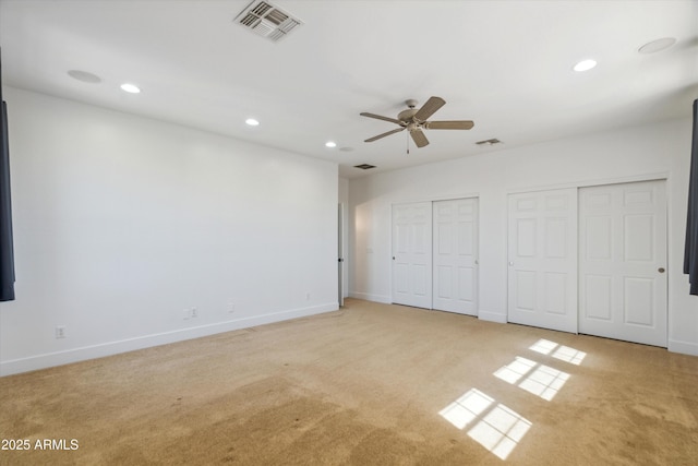 unfurnished bedroom featuring recessed lighting, visible vents, two closets, and light carpet