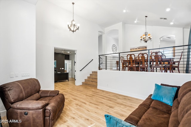 living area featuring stairs, a notable chandelier, wood finished floors, and visible vents