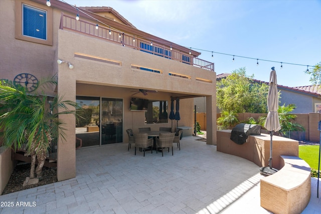 view of patio with a balcony, area for grilling, outdoor dining space, and fence